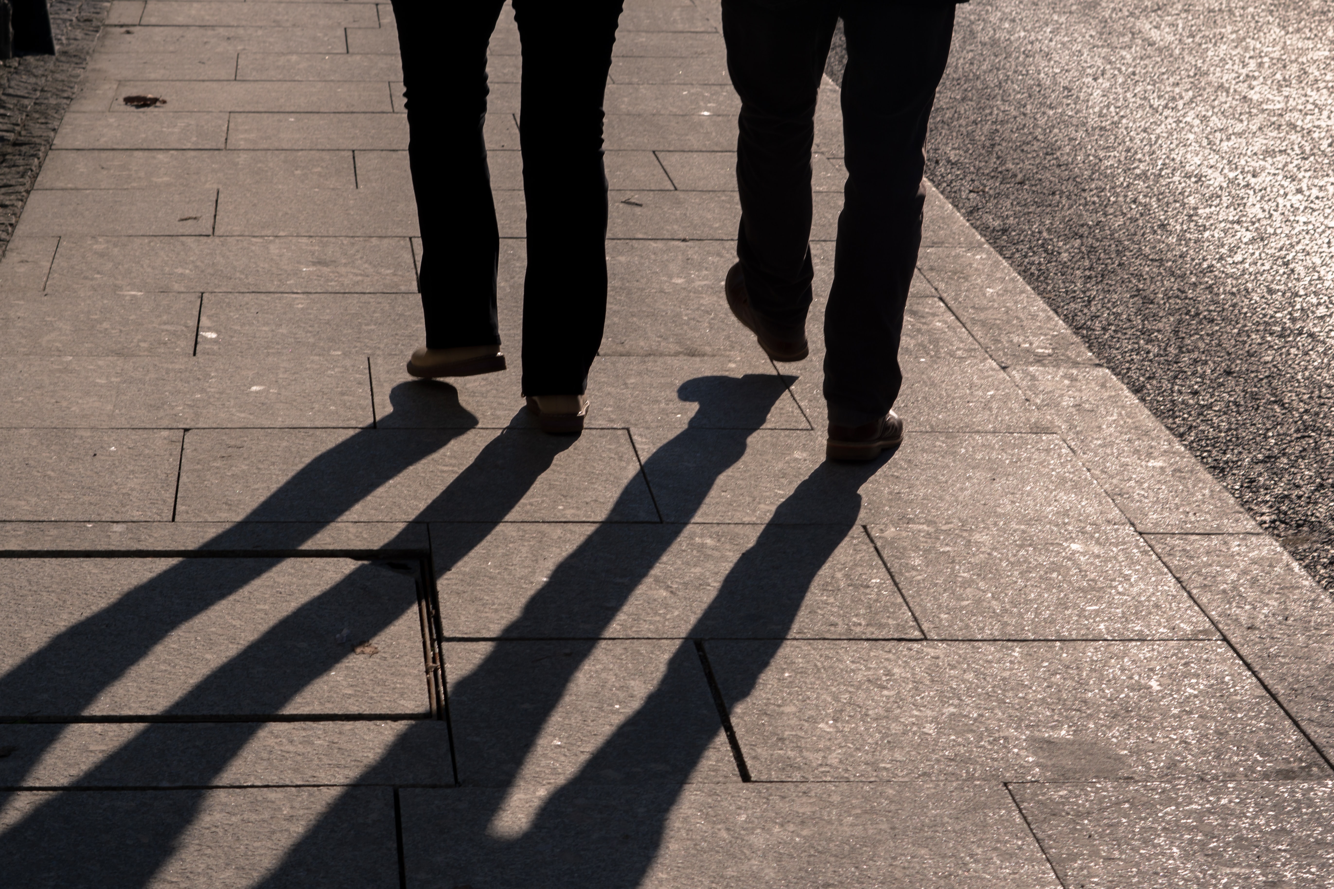 Two people's feet walking on a pavement