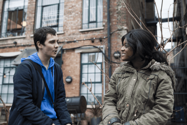 Man and woman having a conversation sat outside a brick building